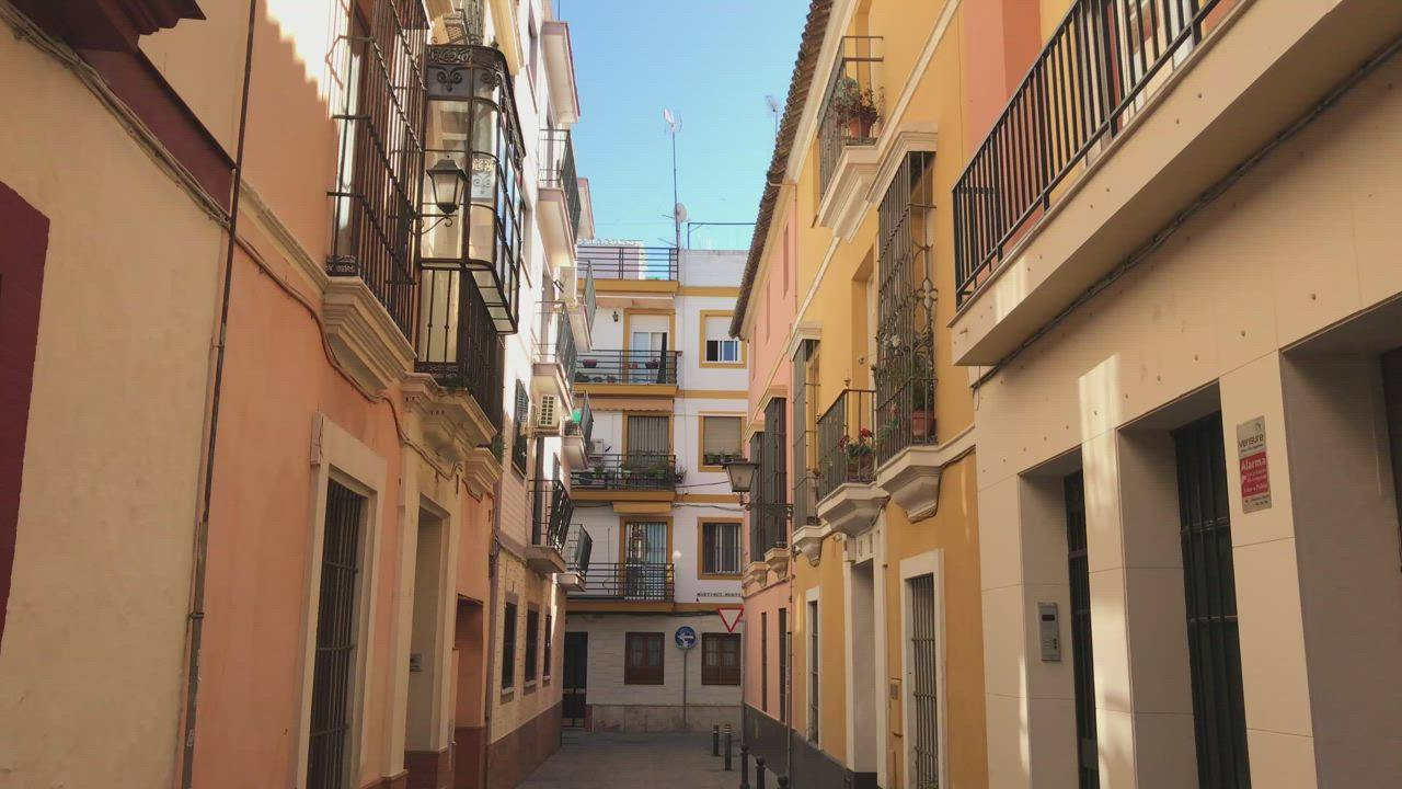 A narrow street of ochre buildings and wrought-iron balconies in Seville